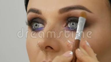化妆师用特殊的画笔、丁香花和珍珠般的烟熏眼影、眼睛和眼影制作出烟熏眼模特